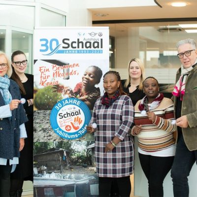 Schaal-Geschäftsleitung und Mitarbeitende vor einem BAnner: 30 Jahre Schaal Jubiläums-Taler - Ein brunnen für Nkando, Kenia